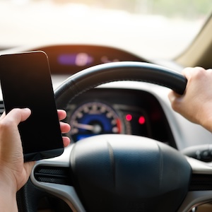 driver holding a smartphone and a steering wheel